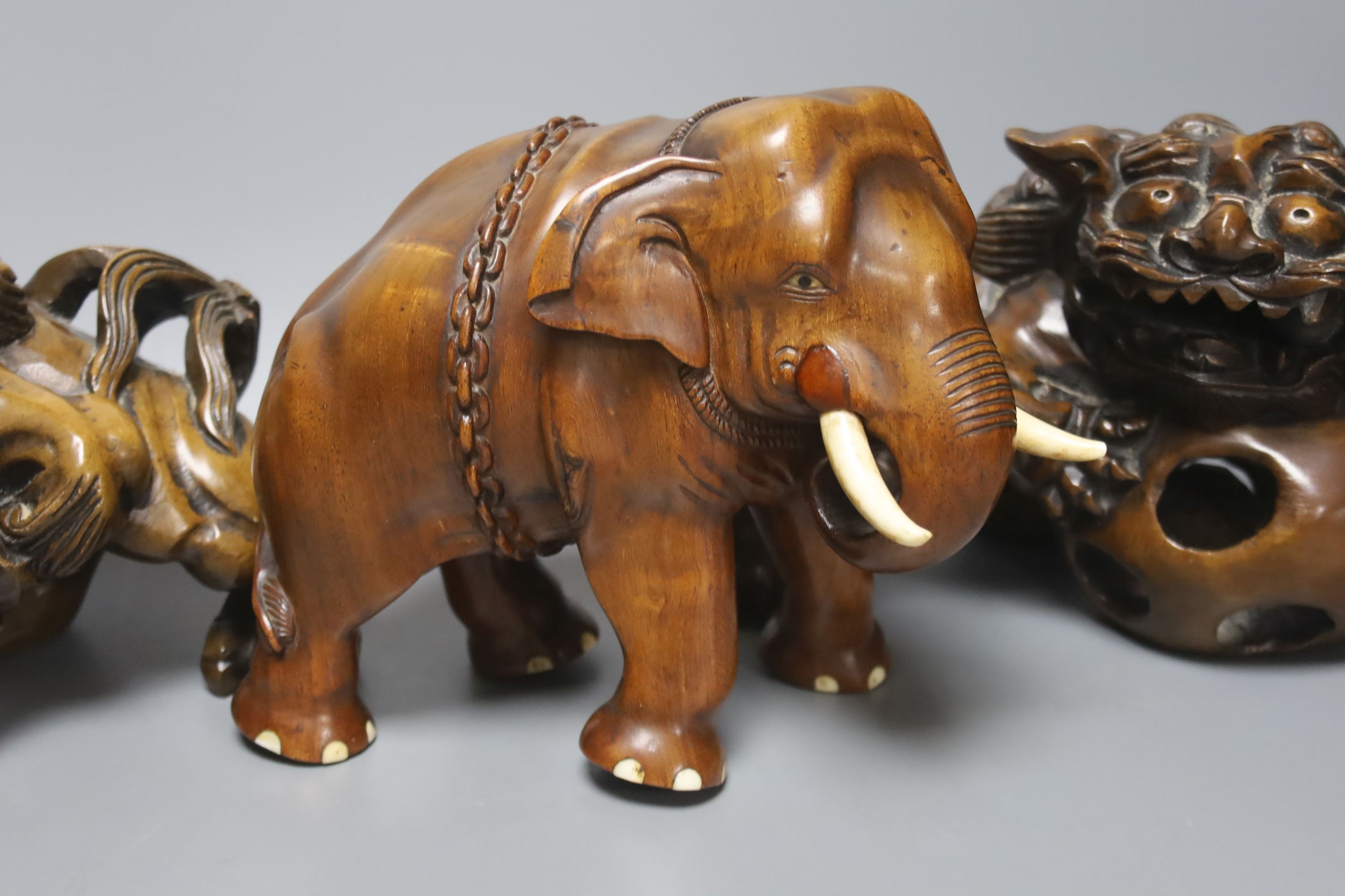 An Indian padouk wood figure of an elephant and a pair of wood figures of Buddhist lions 17cm